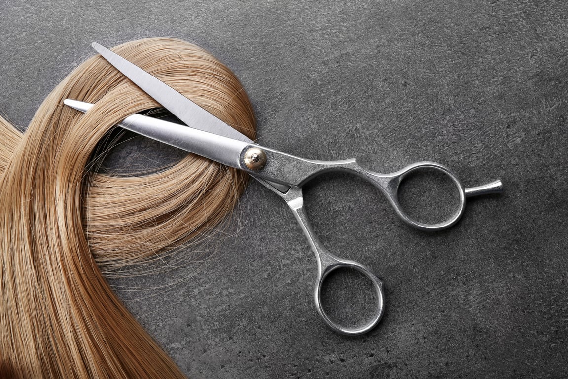 Hairdresser's Scissors with Strand of Blonde Hair on Grey Background